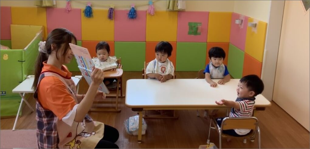 絵本を読み合いする園児と保育士